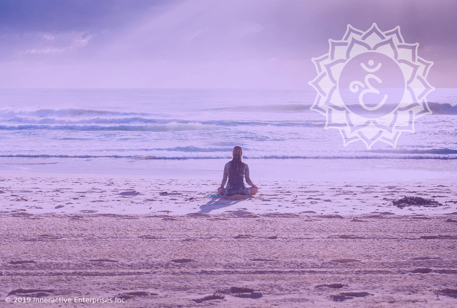 woman meditating in sand by ocean